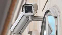 Eine Überwachungskamera ist an einer Wand neben einem Fenster montiert.