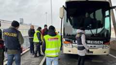 Polizisten und Zollbeamte kontrollieren einen Reisebus an einem Grenzübergang.