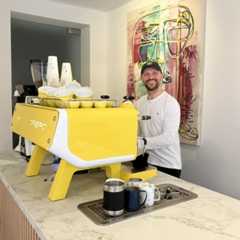 Ein Mann bereitet Kaffee mit einer gelben Espressomaschine zu.