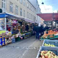Ein belebter Marktstand mit Obst und anderen Waren in einer Stadt.