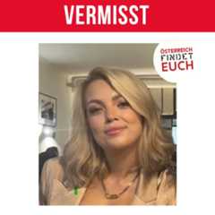 Junge Frau mit schulterlangem blondem Haar und beigem Blazer sitzt in einem Raum und lächelt leicht.