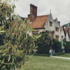 Long-exposure shot of a person walking a path beside the Manor, with its russet roofs and chimney pots reaching to the sky.
