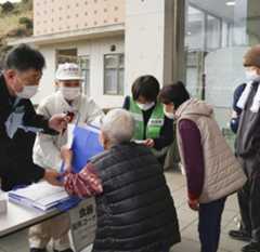 市営住宅などへの入居に向けて、避難所で必要な物資を受け取る被災者(手前)=12日午前、大分市佐賀関