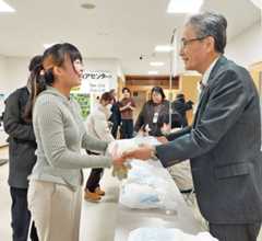 福田学長から米を受け取る弘大生(手前左)=15日午前、弘前大文京町キャンパス