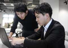 起業した自社の事業について説明する近畿大経済学部4年の越智健心さん（右）。左は起業推進室の垂見俊秀さん＝2025年12月、大阪市鶴見区