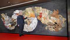 原画や監修を手がけた陶板製の大型レリーフと写真に納まる漫画家大友克洋さん＝15日午前、東京メトロ銀座駅構内