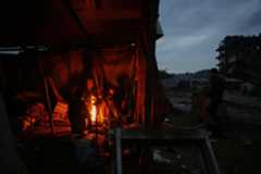 イスラエル軍の攻撃で破壊された跡で、たき火で暖をとる人たち＝12日、ガザ（AP＝共同）