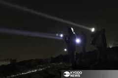 サーチライトを照らして入植者を警戒するパレスチナ人の自警団＝２０２５年１１月、ヨルダン川西岸シンジル（共同）