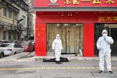 This photo taken on January 30, 2020 shows officials in protective suits checking on an elderly man wearing a facemask who collapsed and died on a street near a hospital in Wuhan. - AFP journalists saw the body on January 30, not long before an emergency vehicle arrived carrying police and medical staff in full-body protective suits. The World Health Organization declared a global emergency over the new coronavirus, as China reported on January 31 the death toll had climbed to 213 with nearly 10,000 infections. AFP/Hector Retamal 