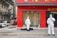 This photo taken on January 30, 2020 shows officials in protective suits checking on an elderly man wearing a facemask who collapsed and died on a street near a hospital in Wuhan. - AFP journalists saw the body on January 30, not long before an emergency vehicle arrived carrying police and medical staff in full-body protective suits. The World Health Organization declared a global emergency over the new coronavirus, as China reported on January 31 the death toll had climbed to 213 with nearly 10,000 infections. AFP/Hector Retamal 