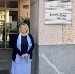 Lidija Ocepek stoji pred Nevrološko kliniko Ljubljana. Oblečena je v modro uniformo za medicinske sestre, čez katero je oblekla temno moder pulover.  Foto: MMC RTV SLO/Ana Vojnović Zorman