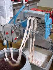 A machine being used to seperate cow intestines into strips