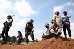 Drusen und Beduinen in Syrien: TOPSHOT - Tribal fighters stand next to a government checkpoint in the town of Busra al-Hariri, east of the city of Sweida, on July 20, 2025, set up to prevent them from advancing towards the city. A ceasefire announced on July 19, appeared to be holding after earlier agreements failed to end fighting between longtime rivals the Druze and the Bedouin that spiralled to draw in the Islamist-led government, the Israeli military and armed tribes from other parts of Syria. (Photo by OMAR HAJ KADOUR / AFP) (Photo by OMAR HAJ KADOUR/AFP via Getty Images)