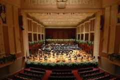 View of the stage from the back of the empty theatre. The stage is laid out for an orchestra.