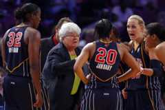 Fever players, in uniform gather around their coach during a game.
