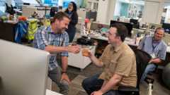indianapolis-star-4-full.jpg In a newspaper office, two men hold glasses and toast each other.