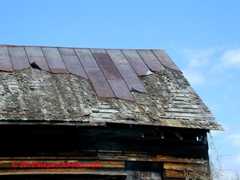 Standing seam metal roof - partly blown off, badly rusted, installed over original wood shingles (C) Daniel Friedman