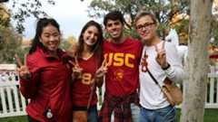 four college students wearing USC shirts smiling and giving the peace sign