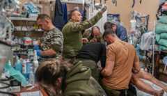 Ukraine war medics A soldier is treated in a small room crowded with medics and supplies.