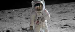 Astronaut in a space suit walking on the moon''s surface, with lunar landscape and dark sky in the background. American flag on the suit.