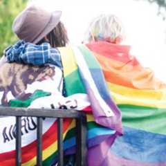 two girls draped in flags backs