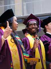 Two students attending graduation in purple and yellow robes