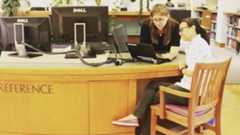 two librarians look at something together at a reference desk