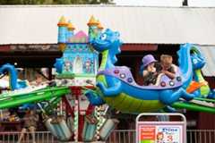 A couple of kids are riding a dragon ride at an amusement park.