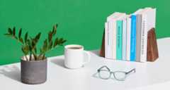 Desk with potted plant, coffee mug, spectacles and marketing books