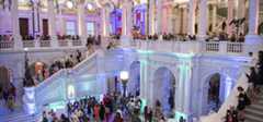 A view of the Great Hall of the Thomas Jefferson Building of the Library of Congress, with many people shown enjoying the beautiful architecture in the hall, on the stairs and in the gallery above