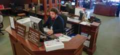 A man sitting at the reference desk while on a computer