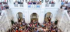 The great hall with hundreds of staff and a banner saying, "Welcome"