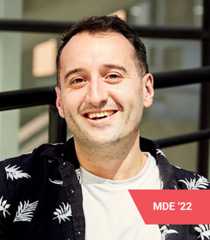 Ed Bayes sitting at a blue table smiling at the camera.