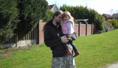 Chris standing up holding his daughter Elva