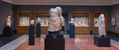 A wide-angle view of a gallery of ancient Roman sculpture with individual marbles on plinths