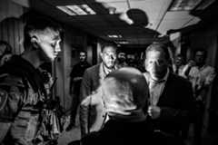 Two men speak to federal agents while spectators watch.