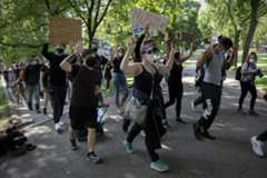 Protesters raise their hands as they march around Boston Common. (Robin Lubbock/WBUR)