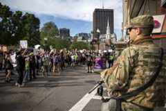 Police and National Guard soldiers watch as demonstrators march down Tremont Street. (Robin Lubbock/WBUR)
