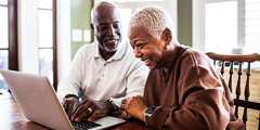 A couple smiles while reviewing information on a laptop