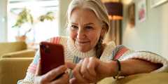 A person smiles while holding their smart phone