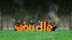 Menschen, die hinter einem Bild mit riesigen „Moodle“-Buchstaben stehen