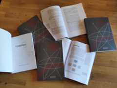 Six books lie on the table, three show the cover and three are open on different pages.