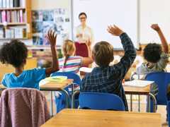 Shot of an unrecognizable group of children sitting in their school classroom and raising their hands to answer a question
