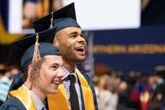 Two students smiling at their graduation ceremony.