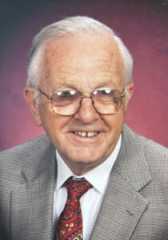 Headshot of James Robinson wearing a gray suit jacket with white dress shirt and red tie.