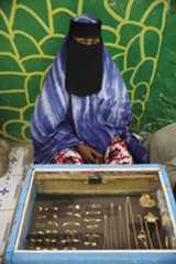 Awoman selling gold from a stall in Hargeisa market sits behind a display case.