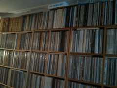 A wall of vinyl LPs with the Smile Sessions box lying horizontally on top of it.