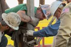 Crew members in hard hats and safety vests from Lighthouse Drilling, Kudu Coring, Mull Companies and the Kansas Geological Survey extract core from the Lyon County well.
