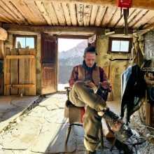 A man in winter regalia sits in a cabin
