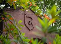 Archway with nautilus shell design surrounded by a tree with green and orange leaves.